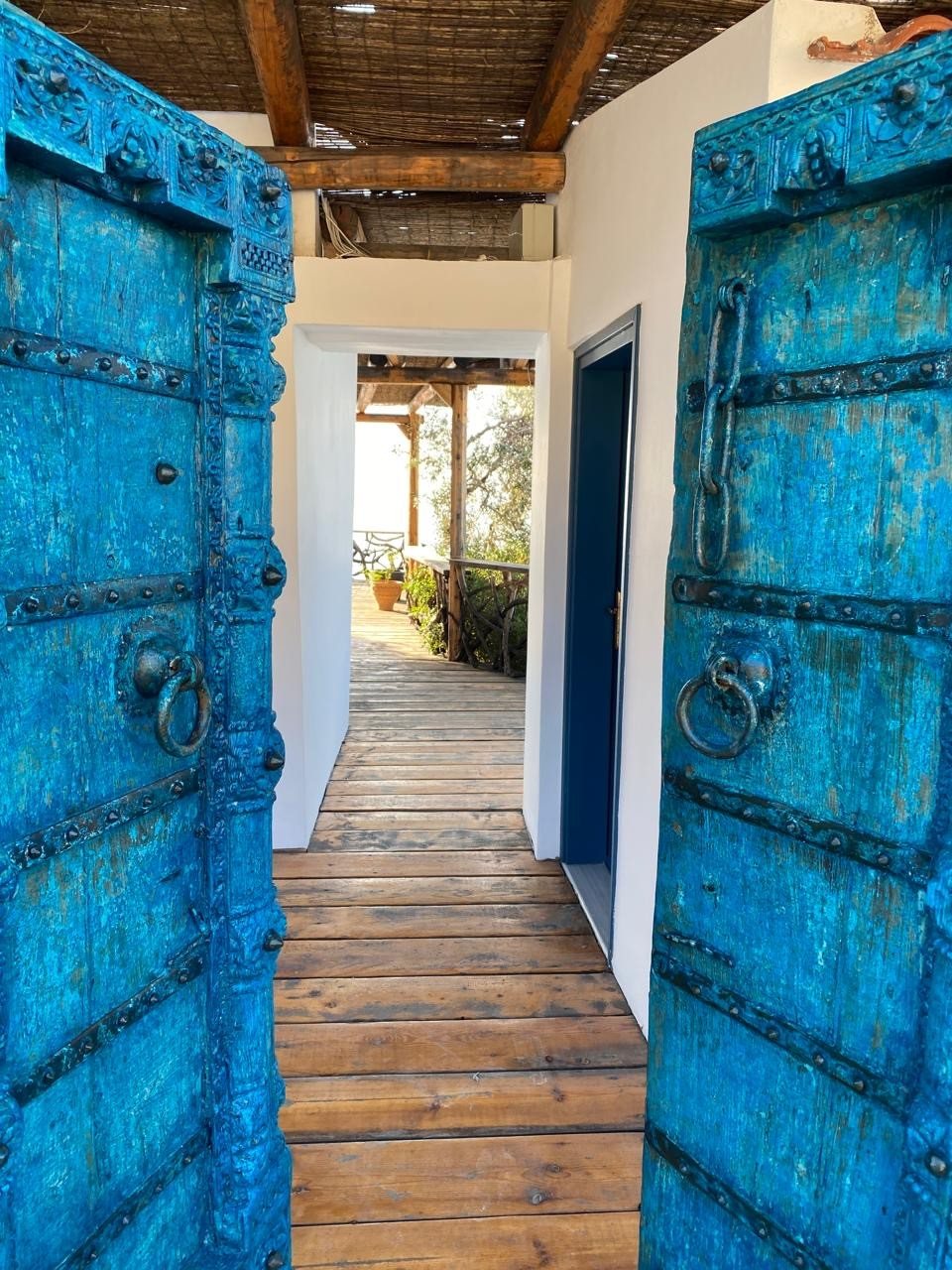 Antique carved blue wooden doors opening through the house to the sea