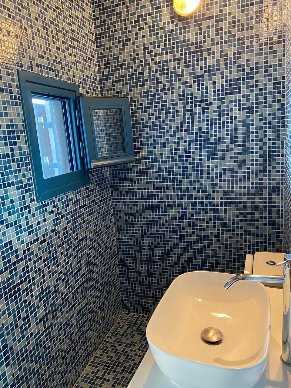 Blue mosaic bathroom with vessel basin and blue-framed window