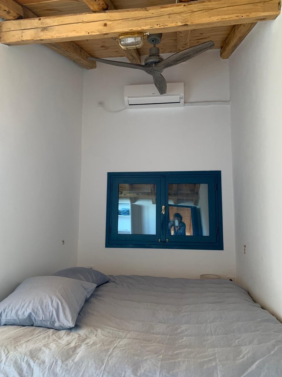 Bedroom with air-conditioning above the bed and a blue window