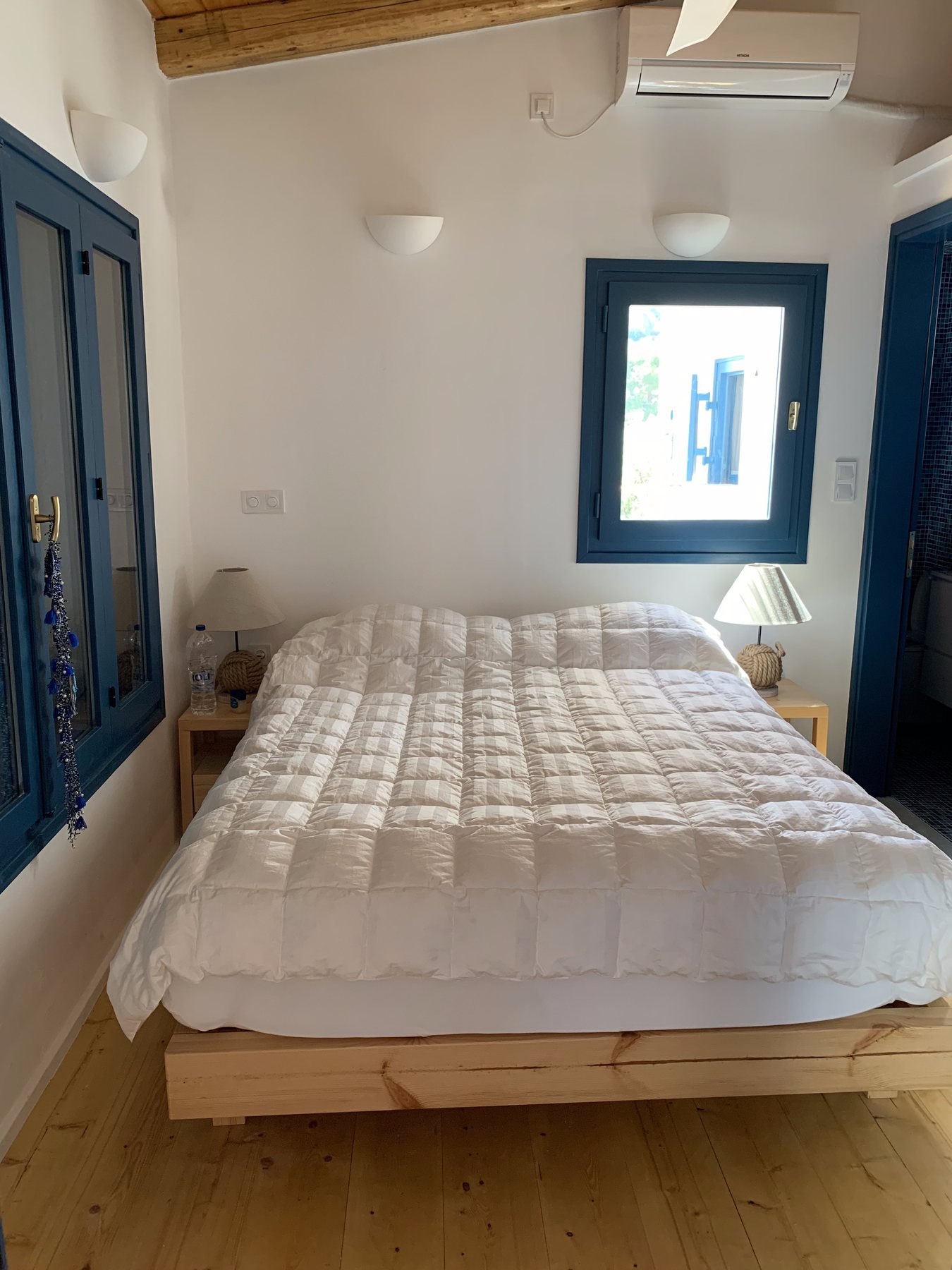 Bedroom with a double bed, blue-framed window and air-conditioning