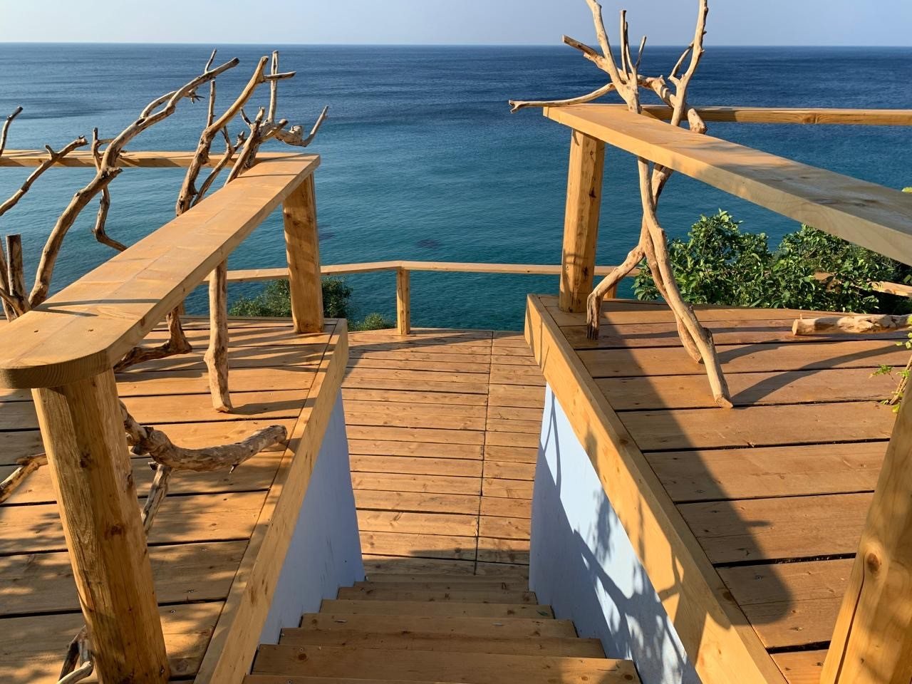 Hand-built driftwood railing along the deck edge over the sea