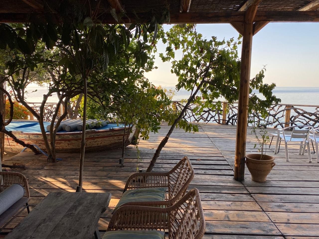 Pergola-shaded deck lounge with loungers and the sea