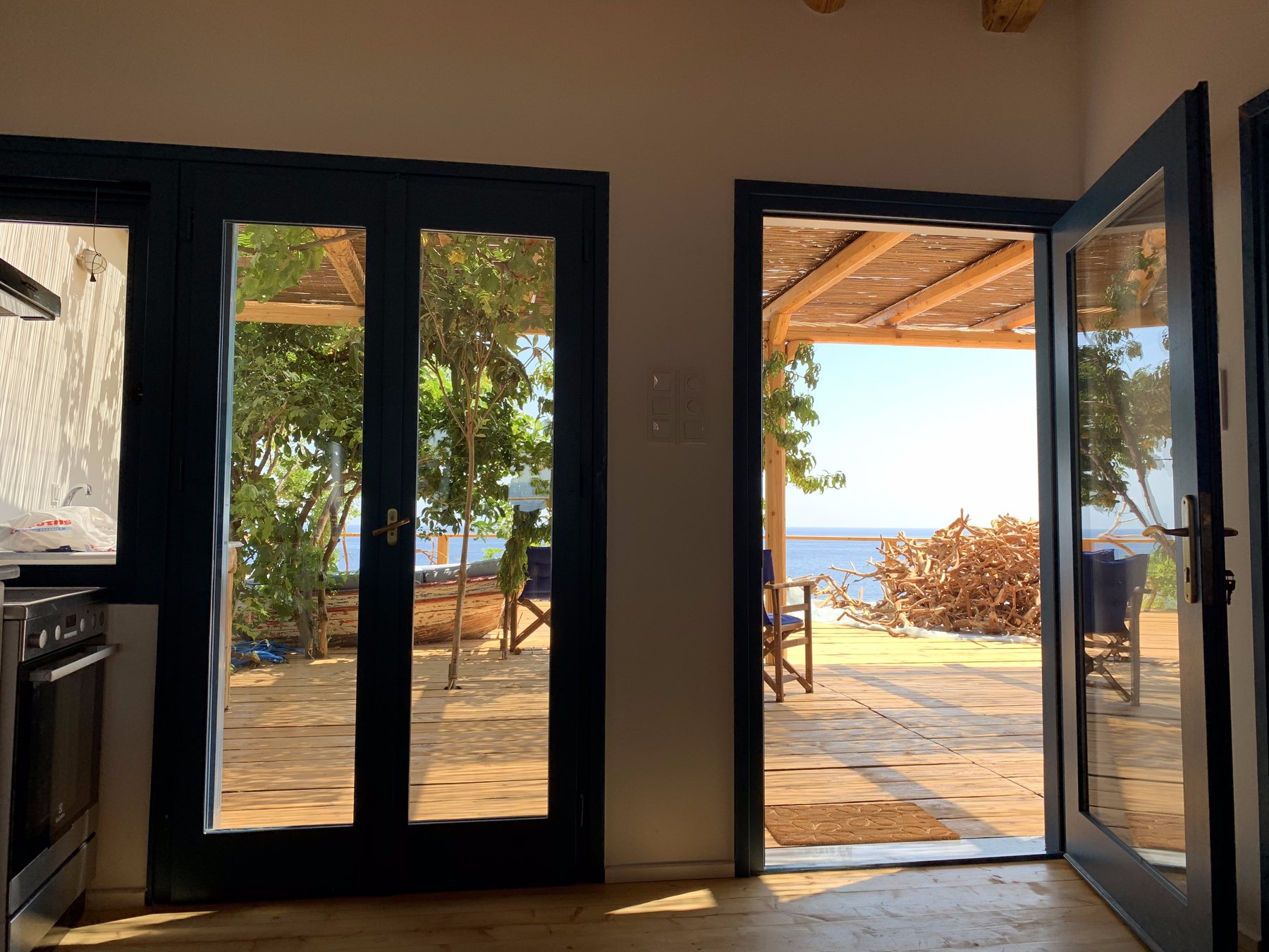 Blue doors open from the house onto the deck and the Aegean at Amodeli
