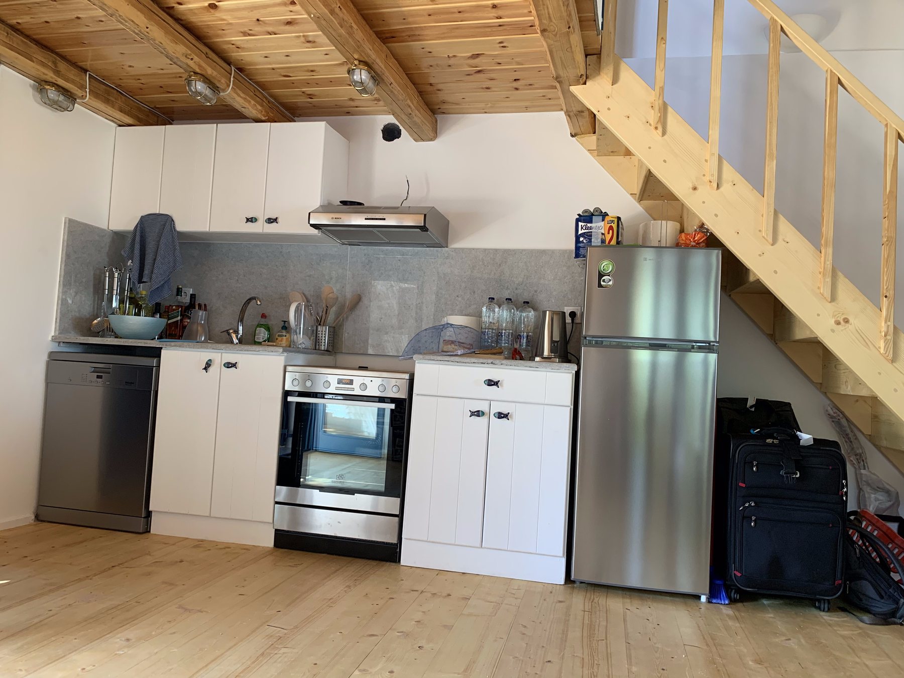 Fitted kitchen with oven, stove, dishwasher and fridge, staircase to the loft