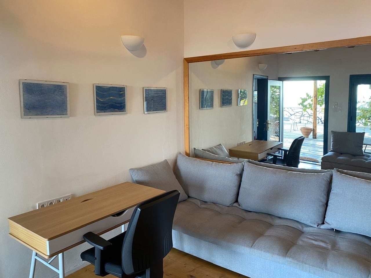 Living room of the second unit with sofa, desk and artwork facing the sea