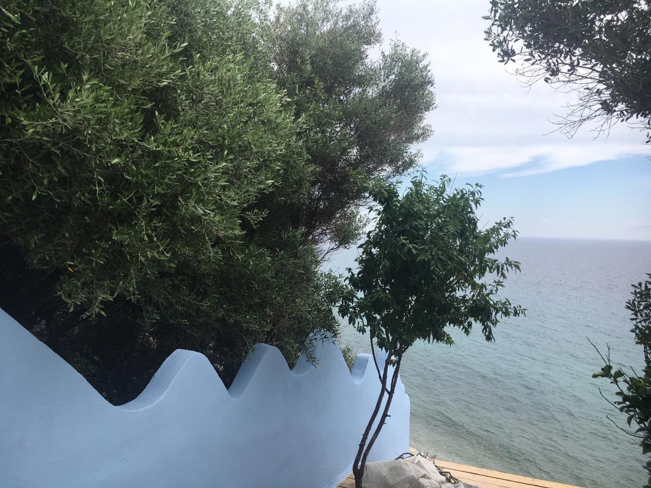 Whitewashed wall with a soft scalloped edge above the sea
