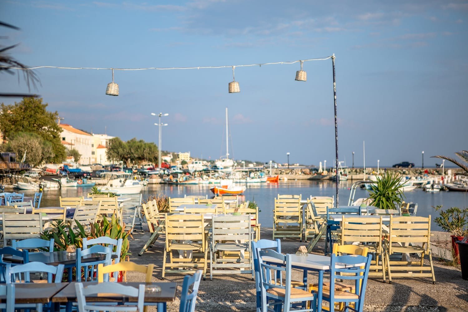 Plomari waterfront taverna chairs facing the harbour at golden hour