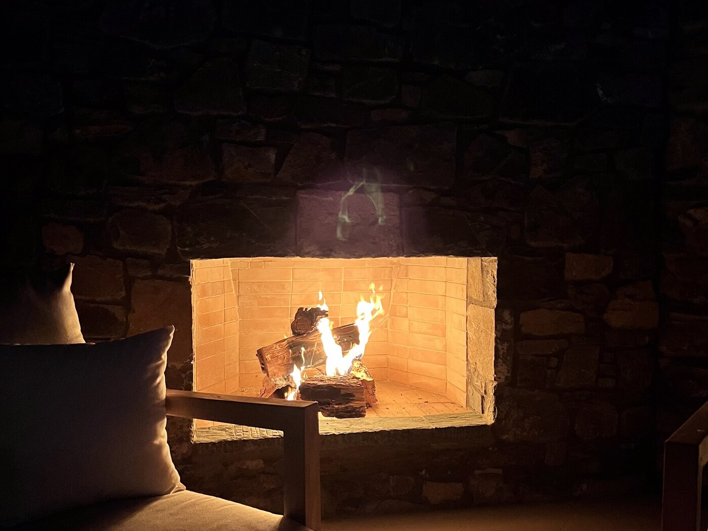 Wood-burning fireplace in the pergola lounge, glowing at night