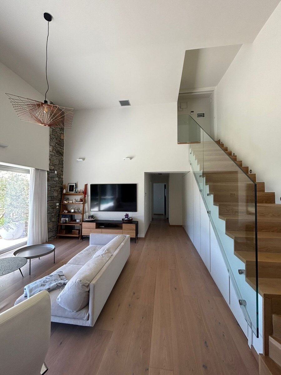 Living room with TV, bookshelves and the glass-railing staircase up to the master