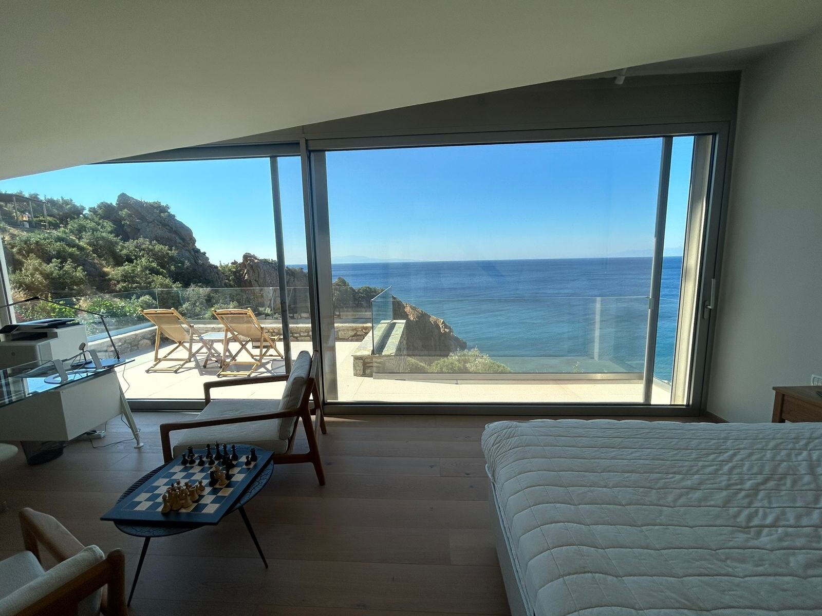 Master suite — bed, sitting area and the Aegean through a wall of glass
