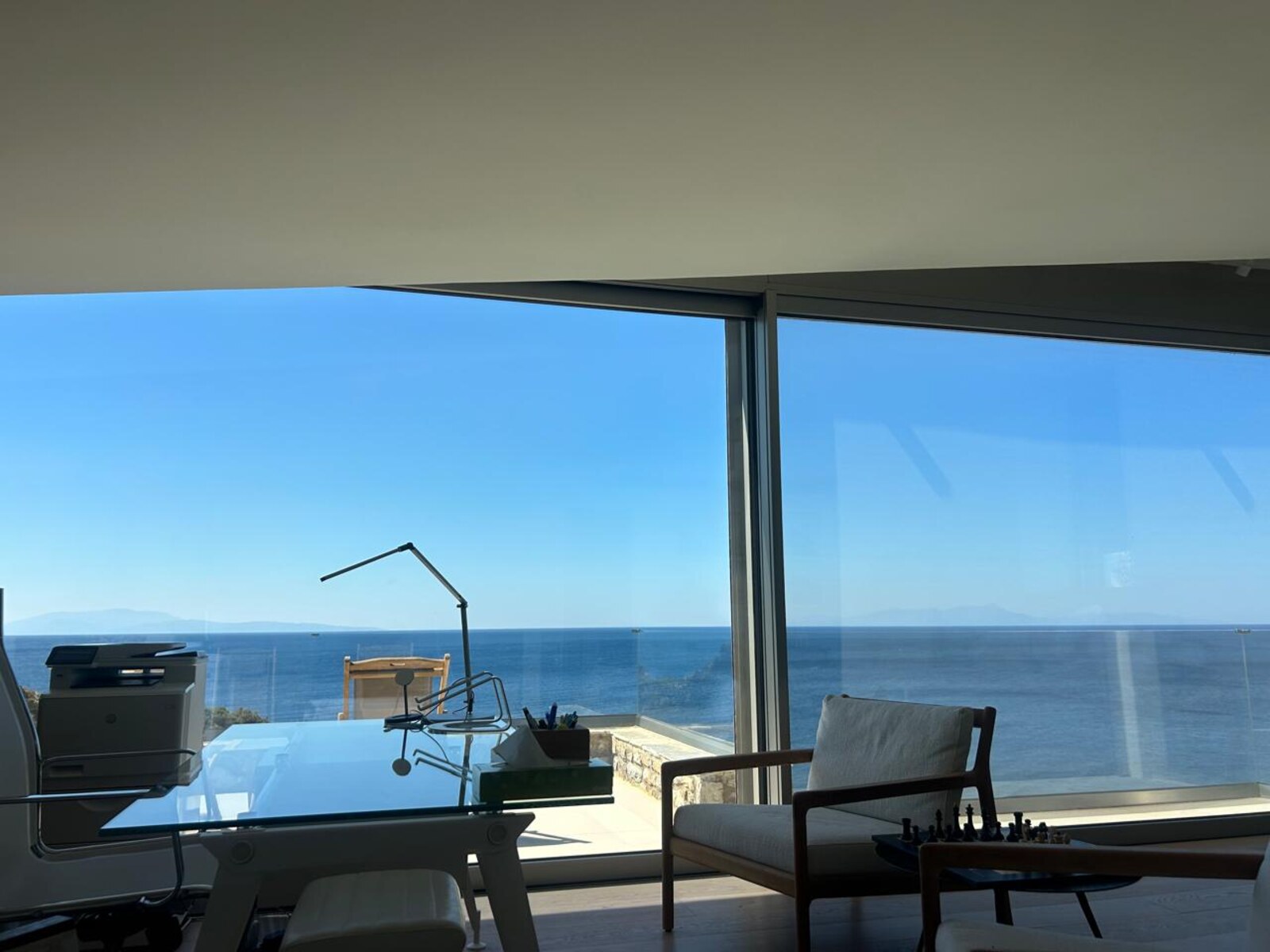 Master suite study with panoramic Aegean view through wraparound glass